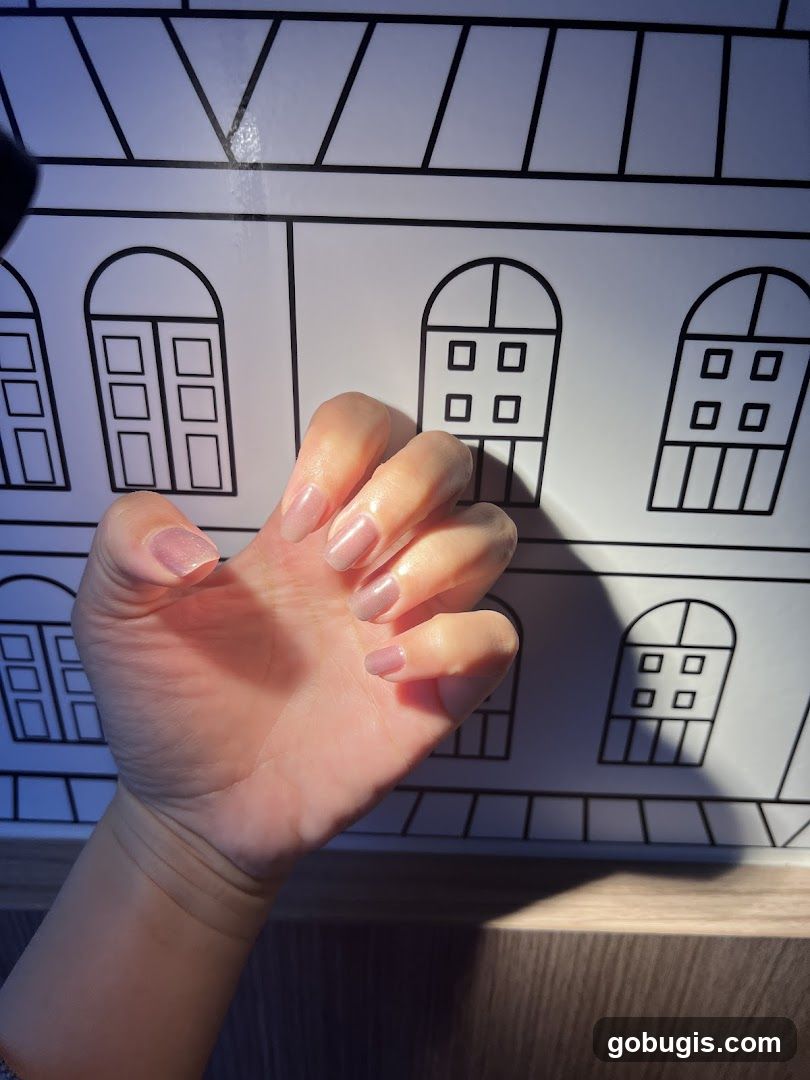 Hand with manicured nails against a backdrop of drawn windows