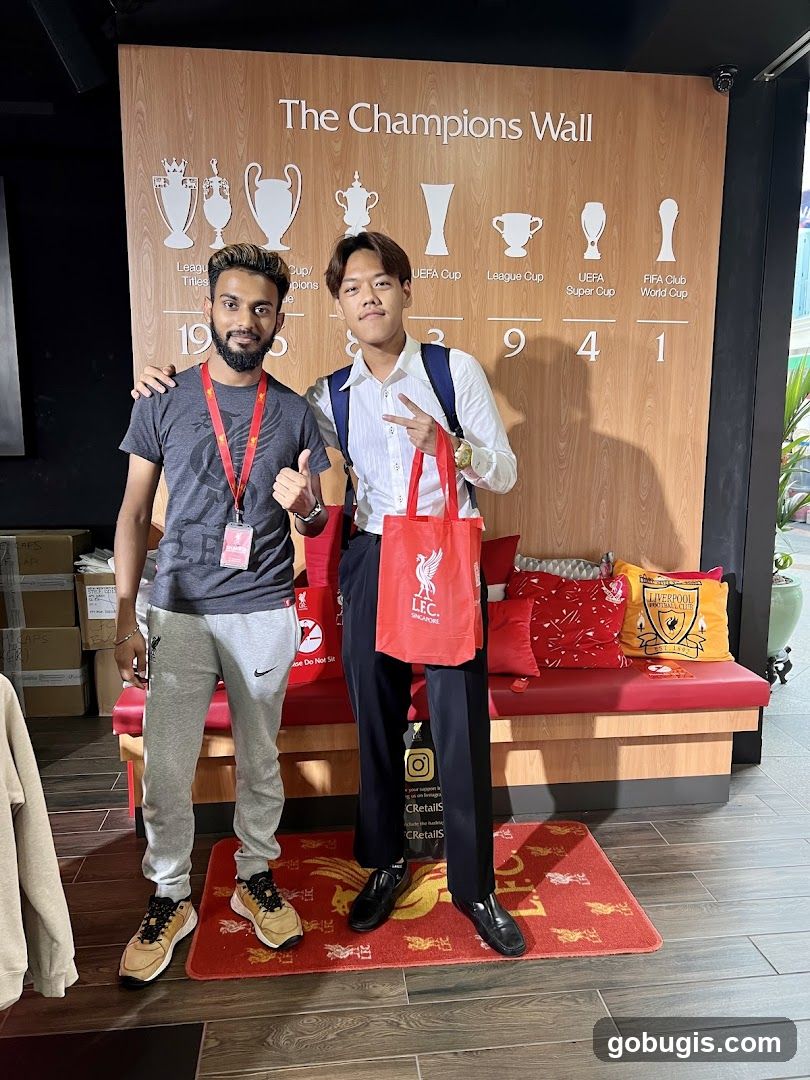 Two men posing in front of a trophy display wall