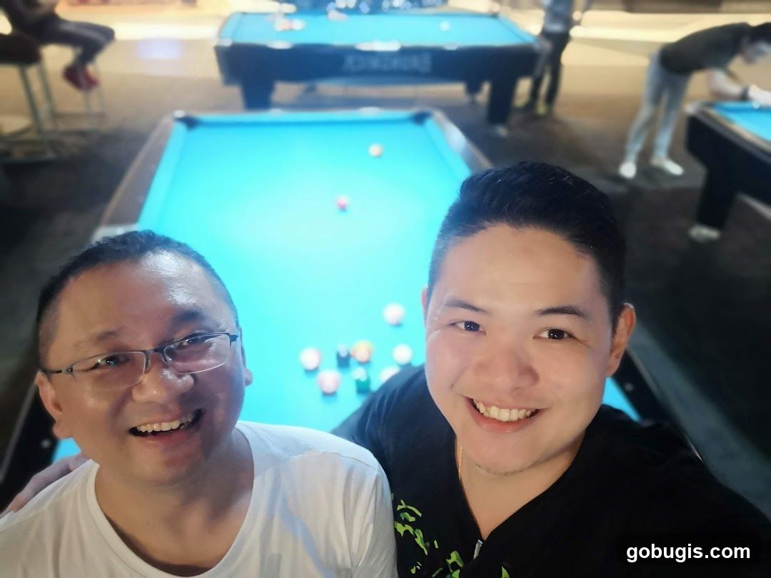 Two men smiling in a pool hall