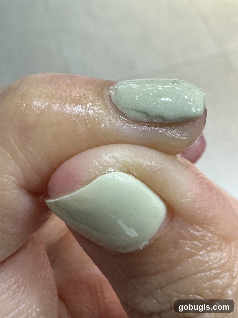 Close-up of a fingernail with light green polish