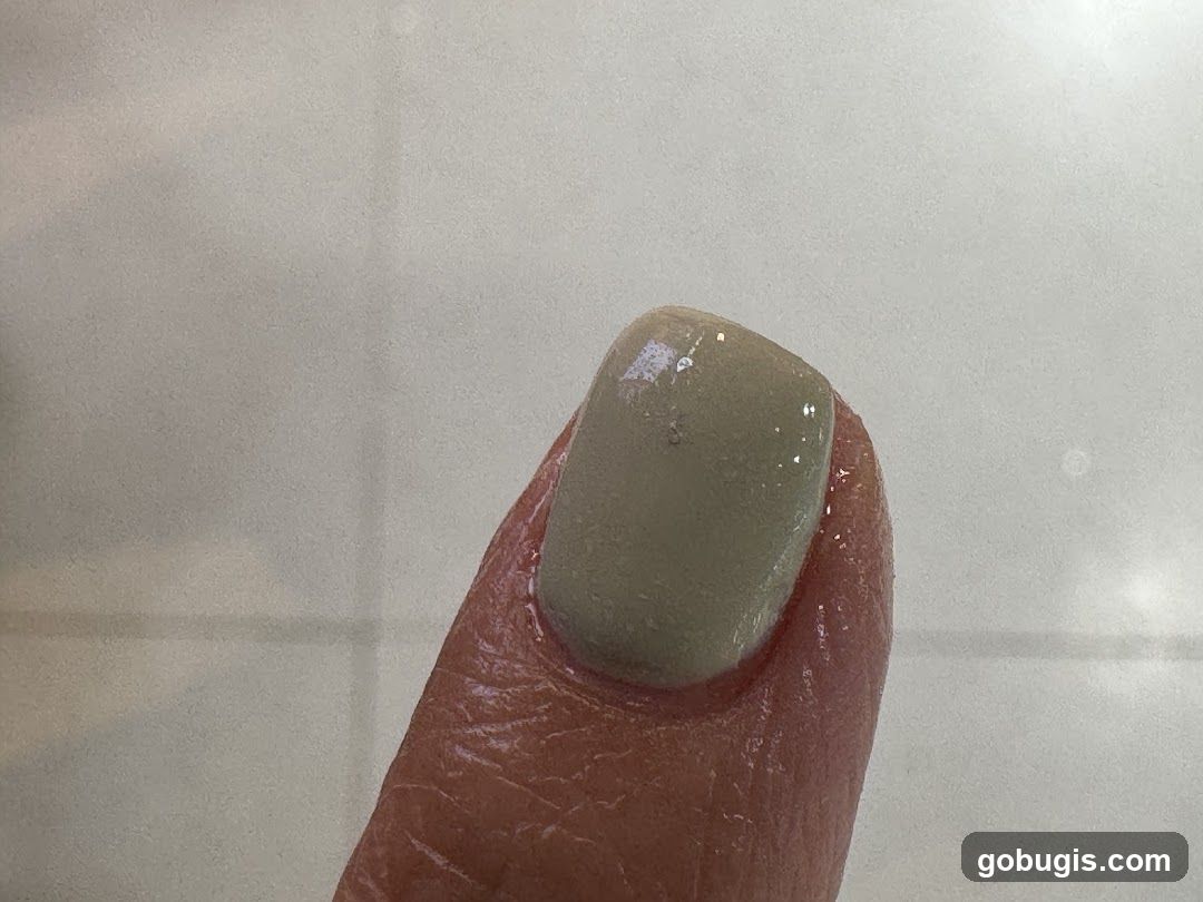 Close-up of a thumb with light green nail polish