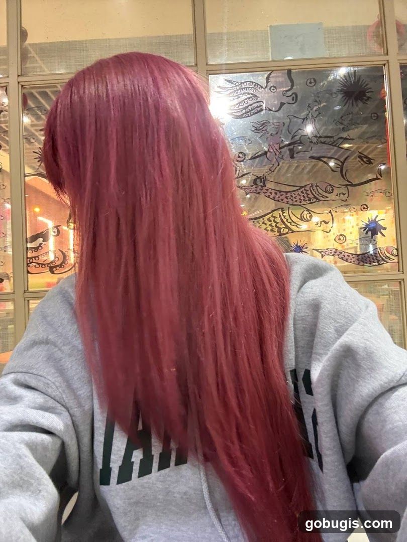 Person with long red hair wearing a grey hoodie