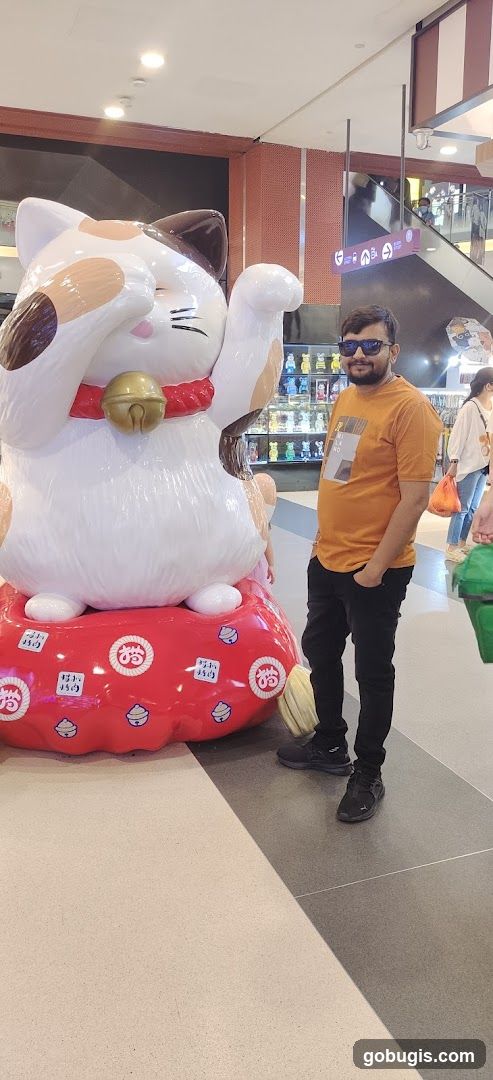 Man posing with a large Maneki-neko statue