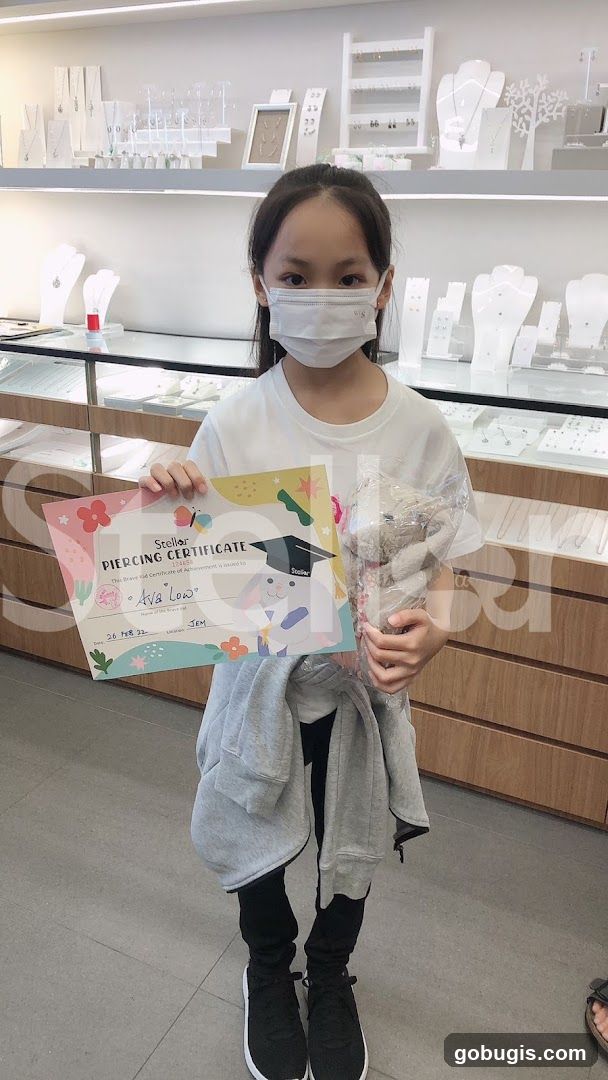 Girl holding a piercing certificate and a stuffed toy