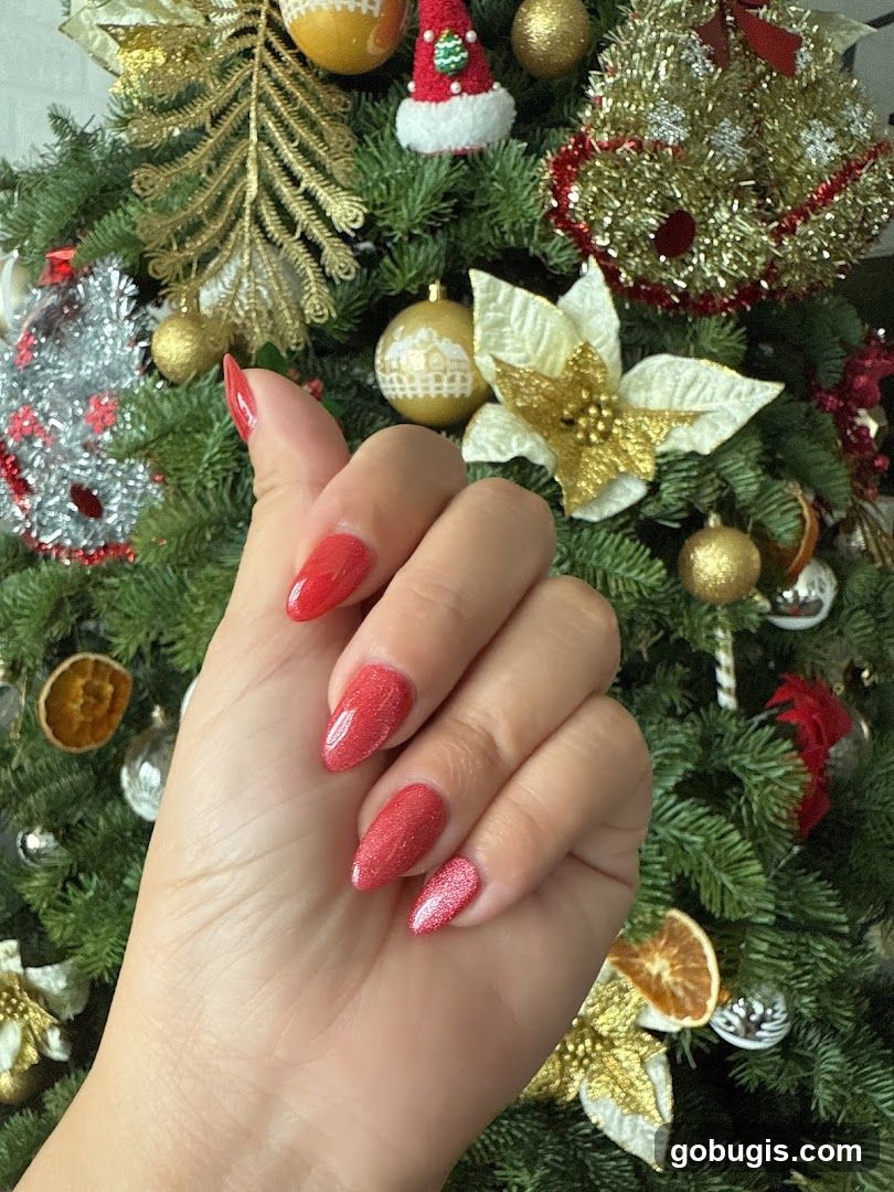 Hand with red nails in front of Christmas tree