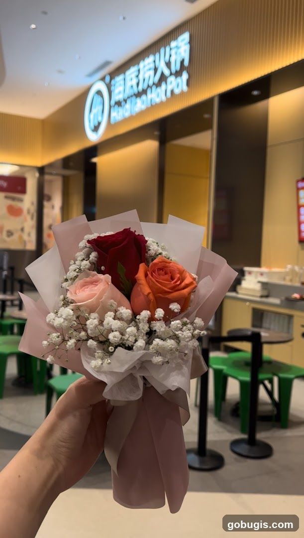 Hand holding a bouquet of roses in front of a restaurant