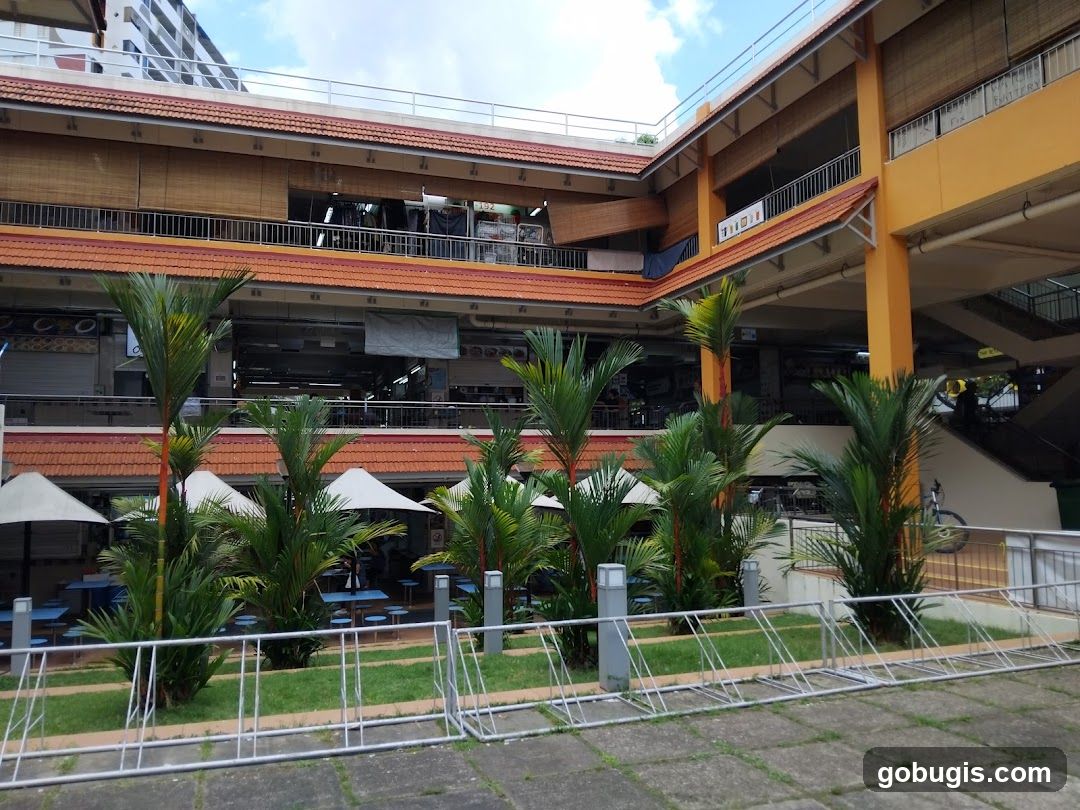 Outdoor seating area with palm trees and shops in the background