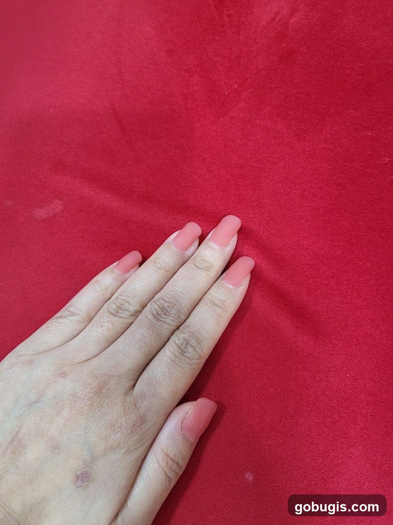 Hand with Pink Nails on Red Fabric