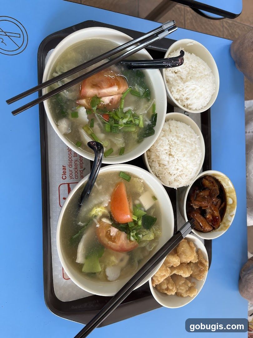 Two bowls of soup with rice and side dishes