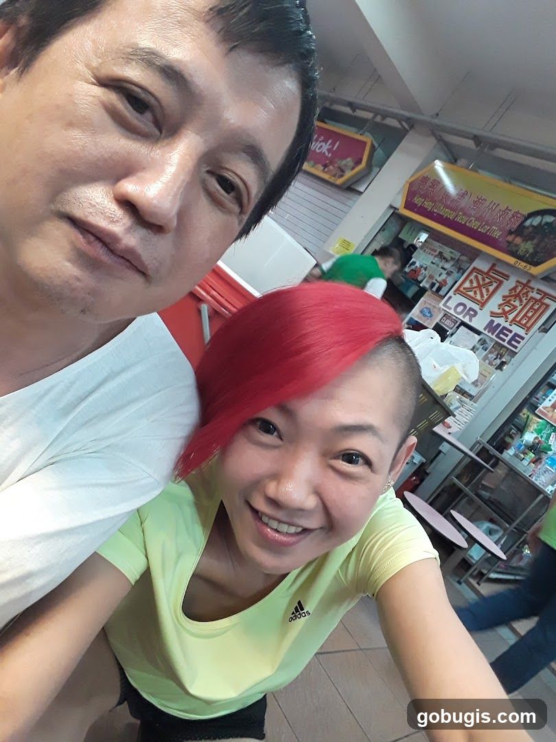 Two people taking a selfie in front of a food stall