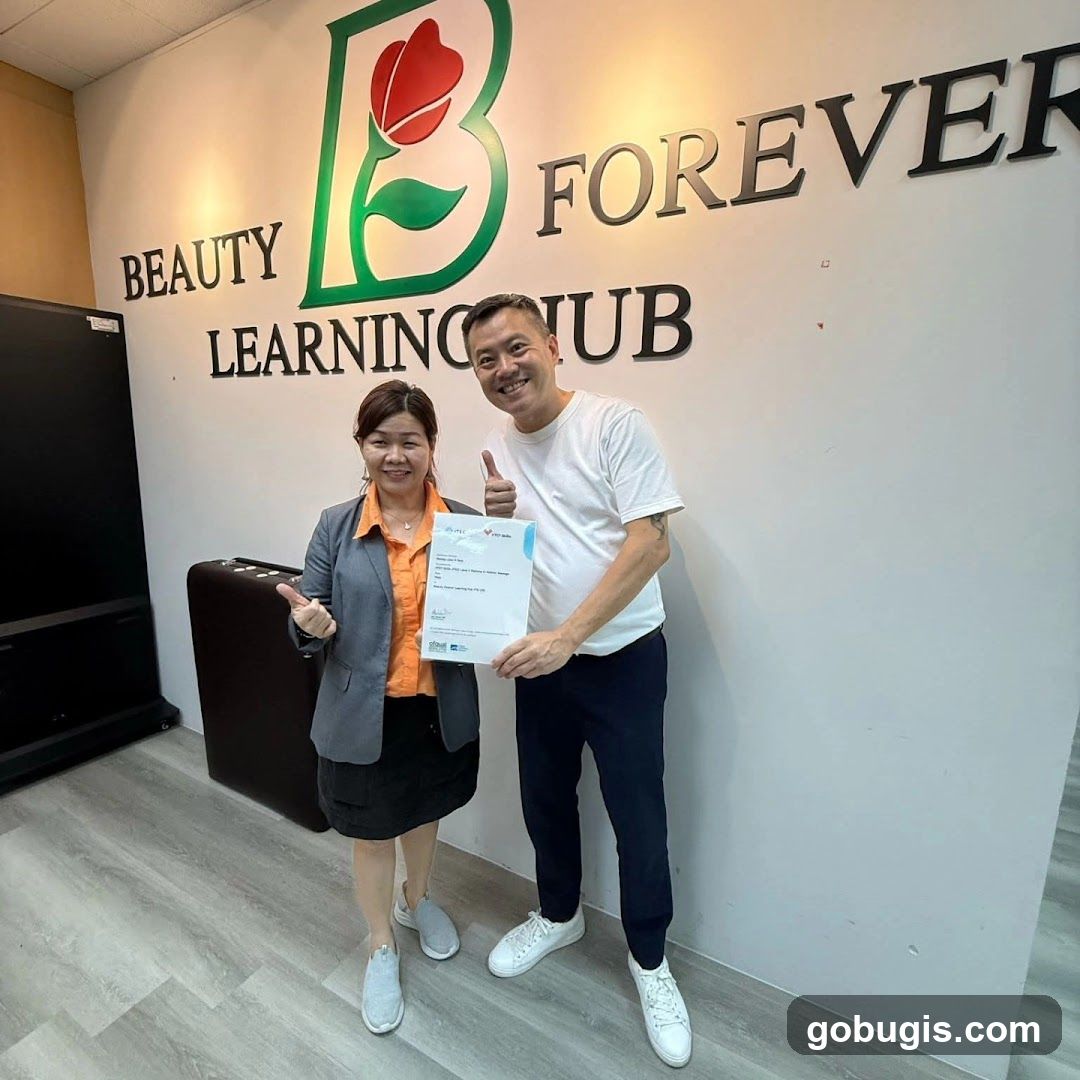 Two people holding a certificate in front of a wall with a logo