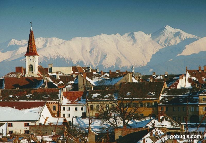 Snow-Covered Rooftops with Mountains in the Background