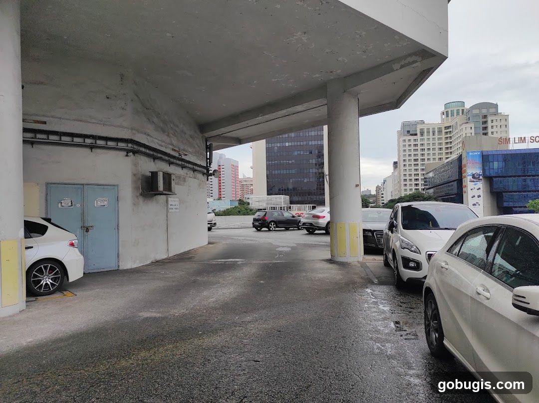 Cars parked under a concrete structure with buildings in the background