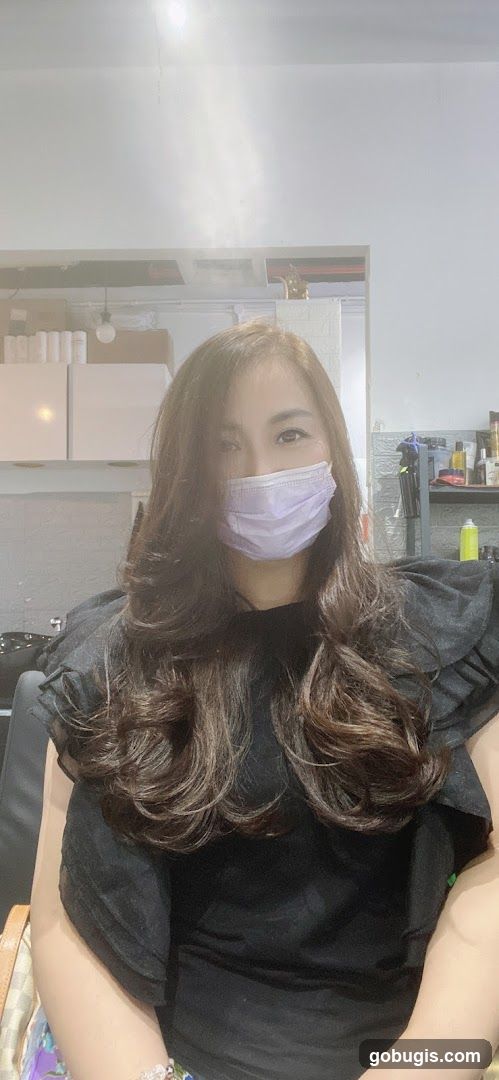 Woman with long brown hair wearing a mask