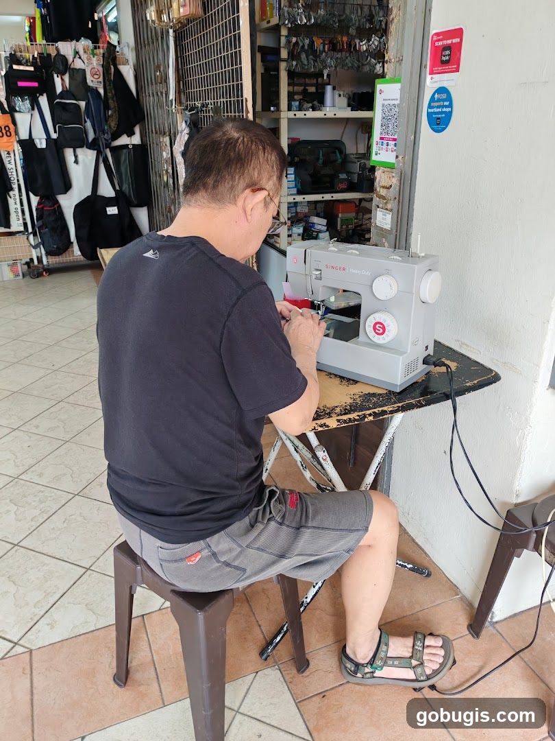 Man sewing at a table outside a shop