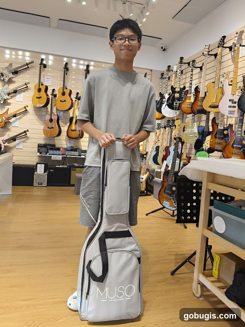 Young man holding a guitar case in a music store