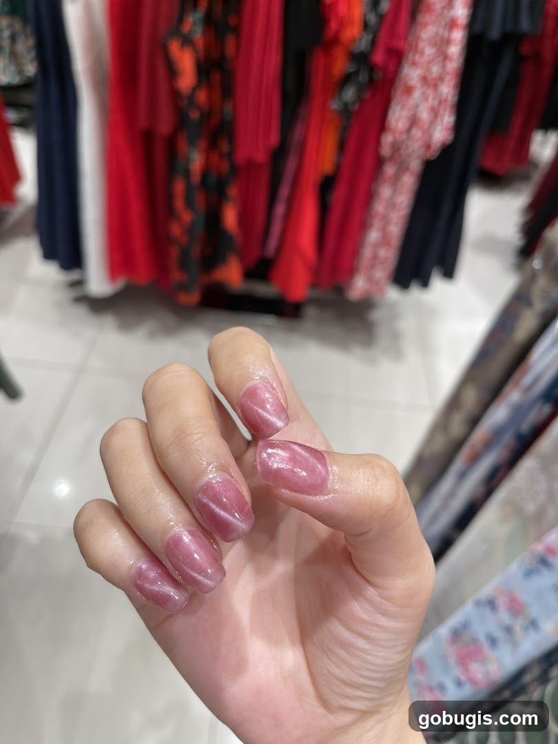 Woman's Hand with Pink Cat Eye Nails in Clothing Store