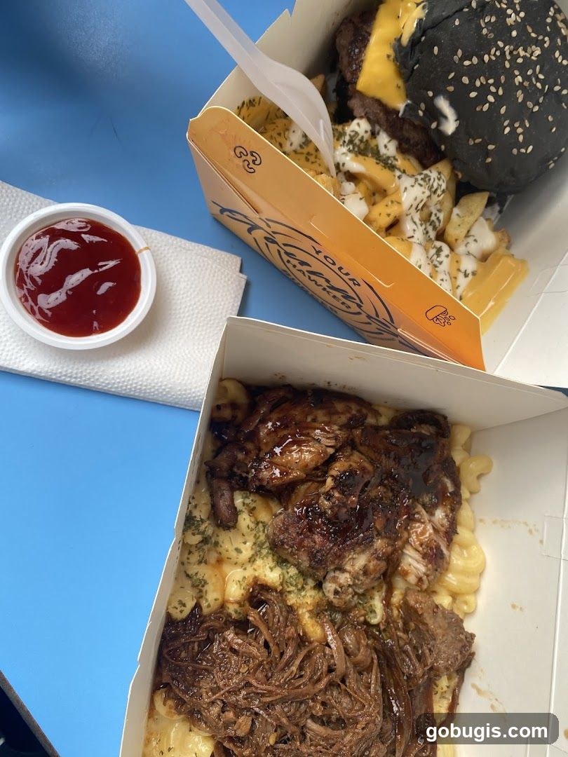 Food boxes with mac and cheese, pulled meat, chicken, and fries with a burger
