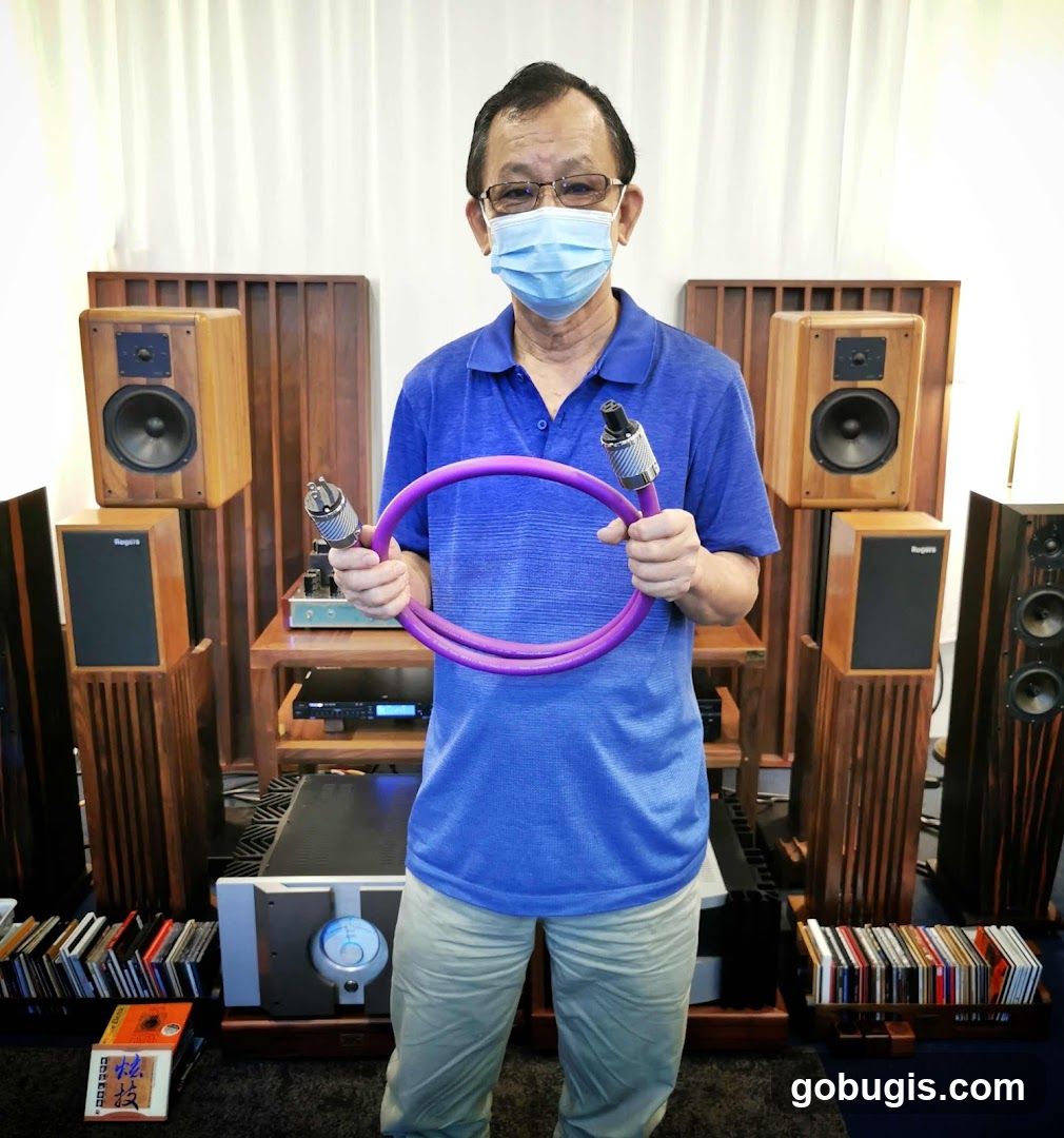 Man holding audio cable with speakers in background