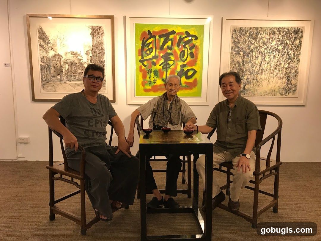 Three men seated at a table in front of artwork
