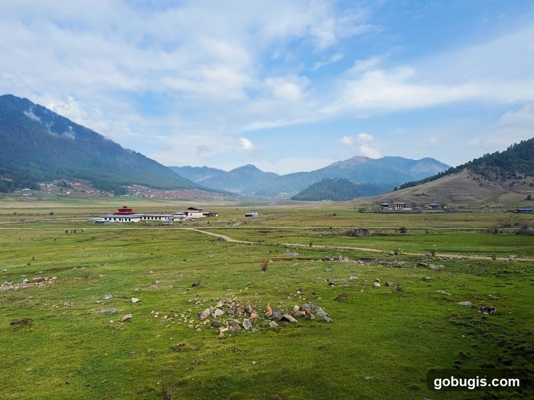 Vast Green Valley with Mountains and Buildings