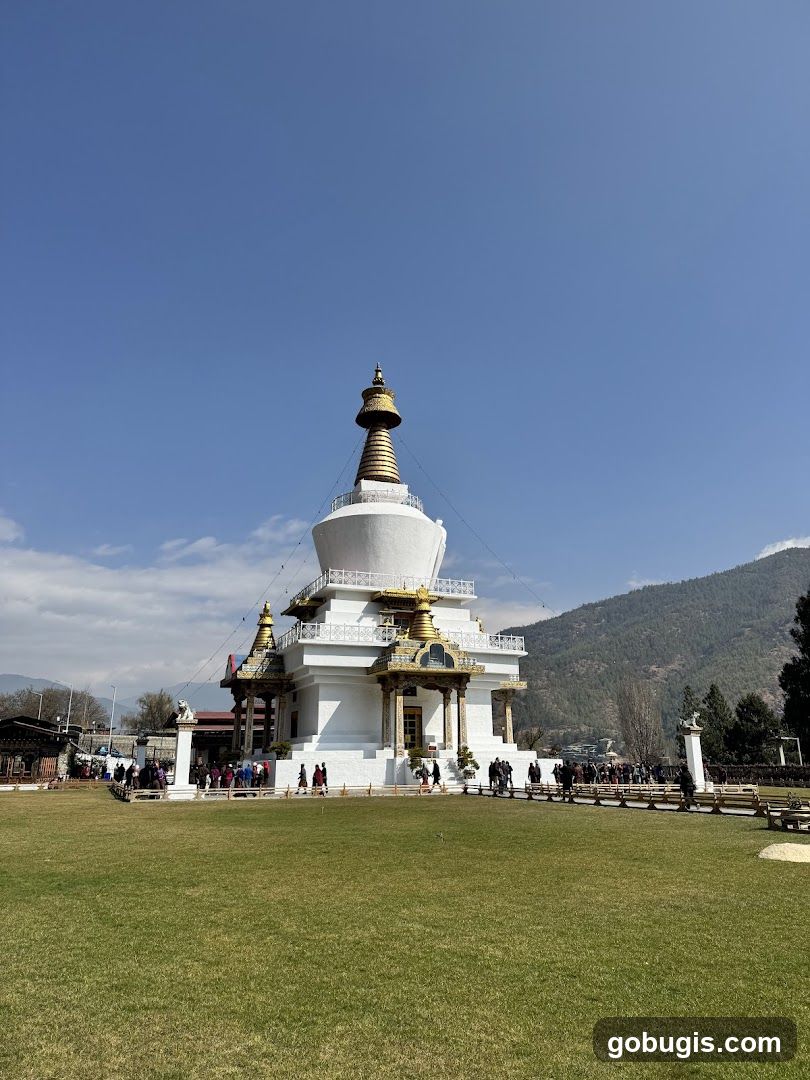 A white stupa with golden accents stands tall against a clear blue sky.