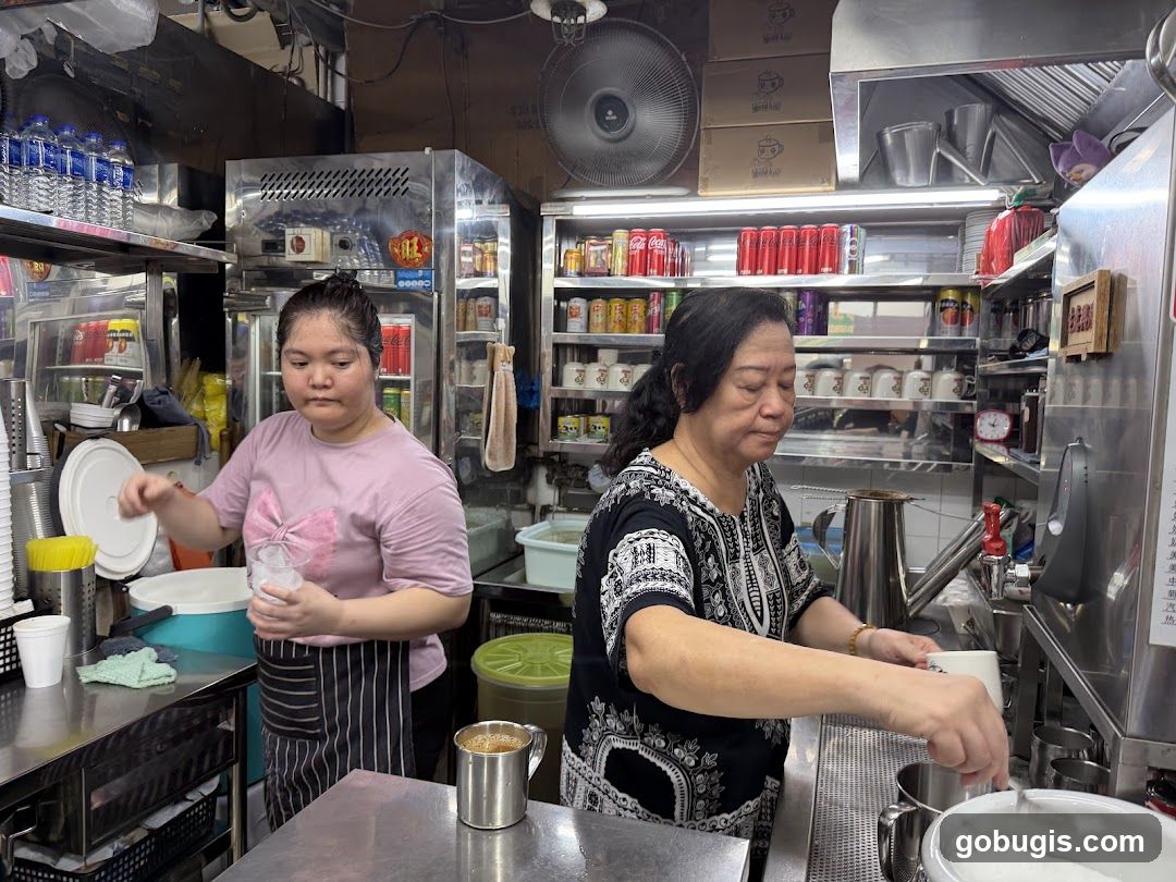 Two women preparing drinks in a busy food stall
