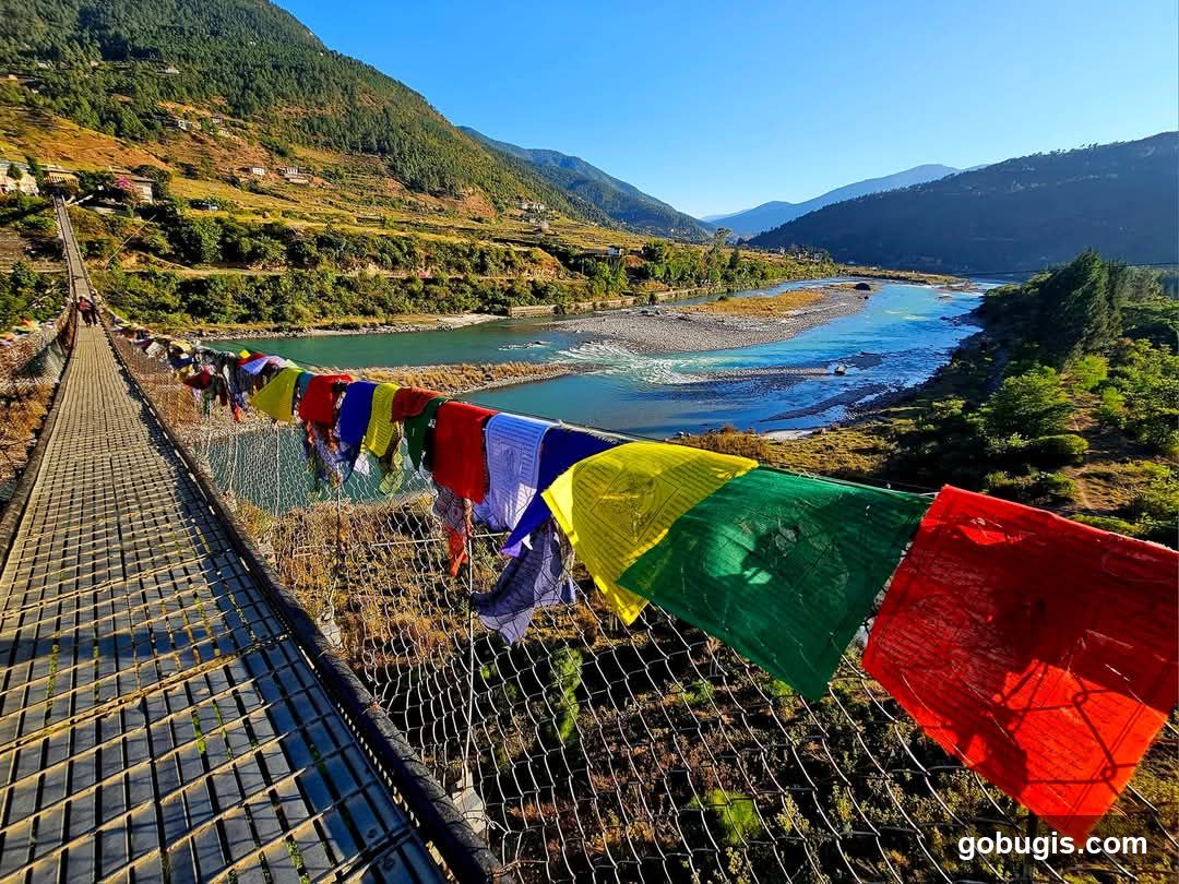 Suspension bridge with prayer flags over a river