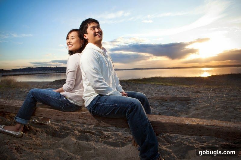Couple sitting on a log at sunset