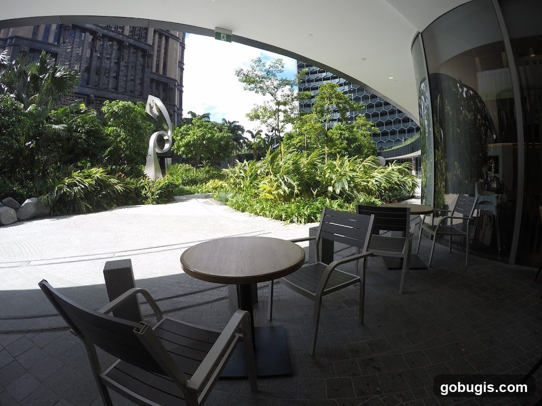 Outdoor seating area with modern sculpture and lush greenery