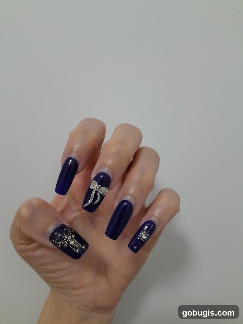 Nails with dark blue polish and embellishments