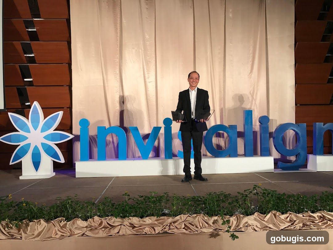 Man holding awards on stage with Invisalign logo
