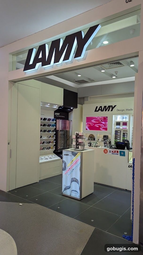 The exterior of a Lamy store, featuring the prominent Lamy logo above the entrance. Inside, displays showcase a variety of pens and writing instruments.