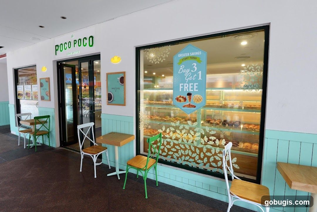 The exterior of a bake shoppe with a large display window showcasing various pastries. The shop's name, "POCO POCO BAKE SHOPPE", is visible above the entrance. There are outdoor seating areas with tables and chairs. A promotional sign in the window reads "GREATER SAVINGS START TODAY Buy 3 Get 1 FREE".