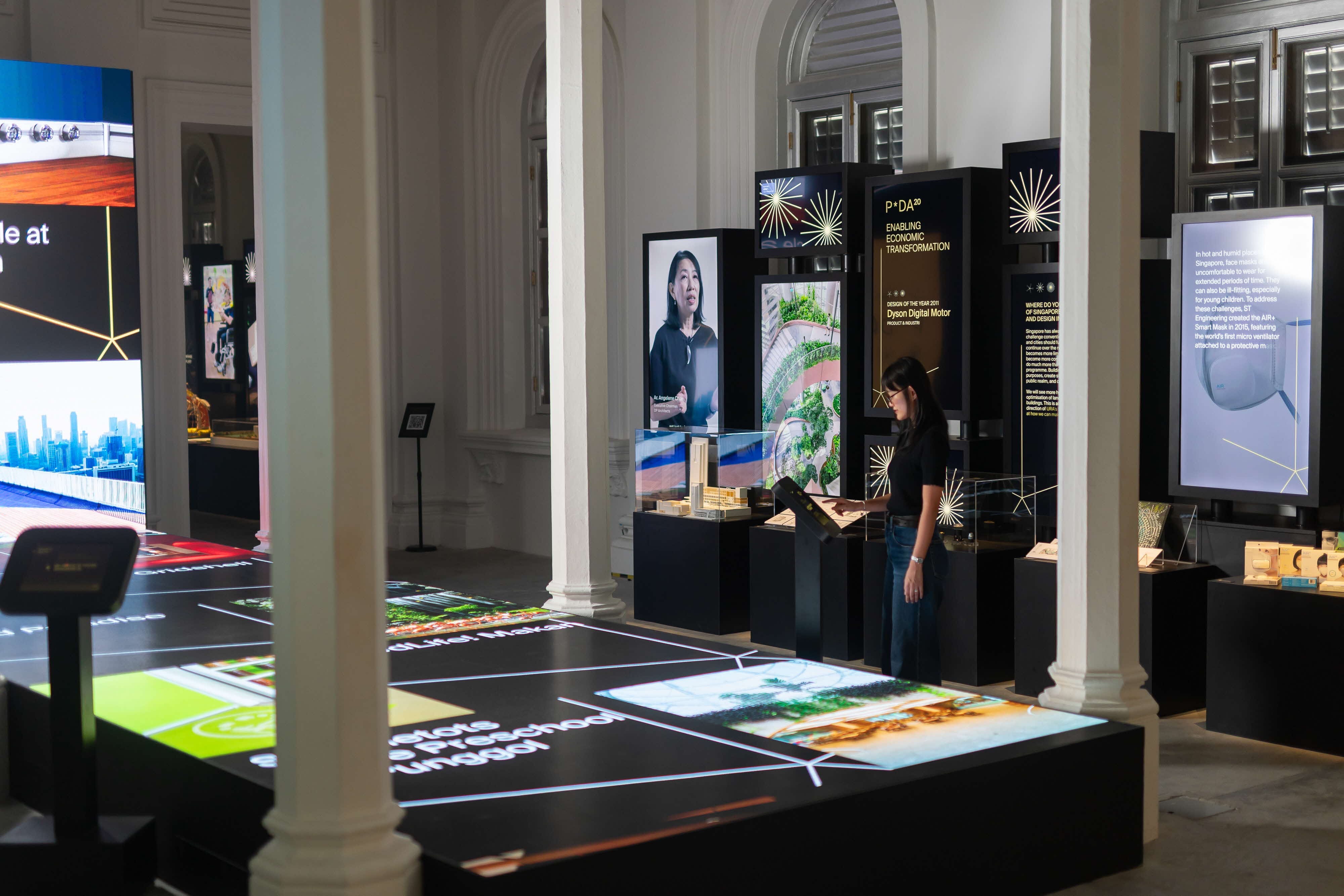 Visitor using a console beside the LED floor atlas in Stamford Gallery, with the Enabling Economic Transformation bay and Dyson Digital Motor panel behind