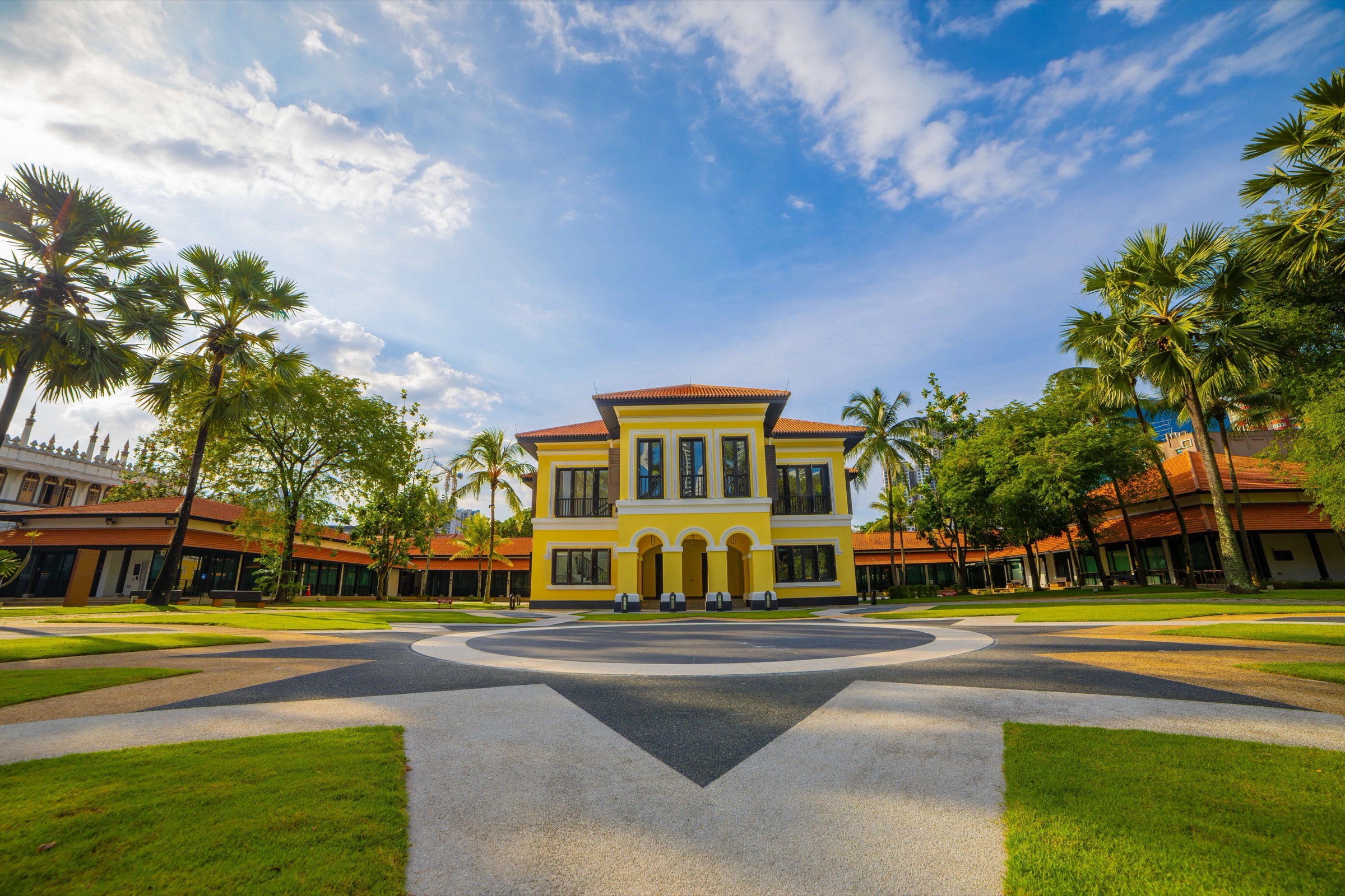 Yellow Istana Kampong Gelam at the Malay Heritage Centre, with the lawn and compass paving in front of the palace